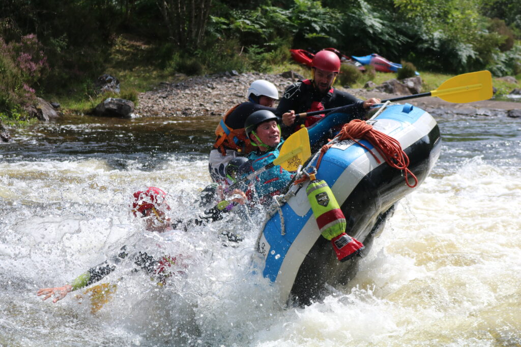 A group of people wearing safety gear, enjoying an Active Outdoor Pursuits white water rafting adventure